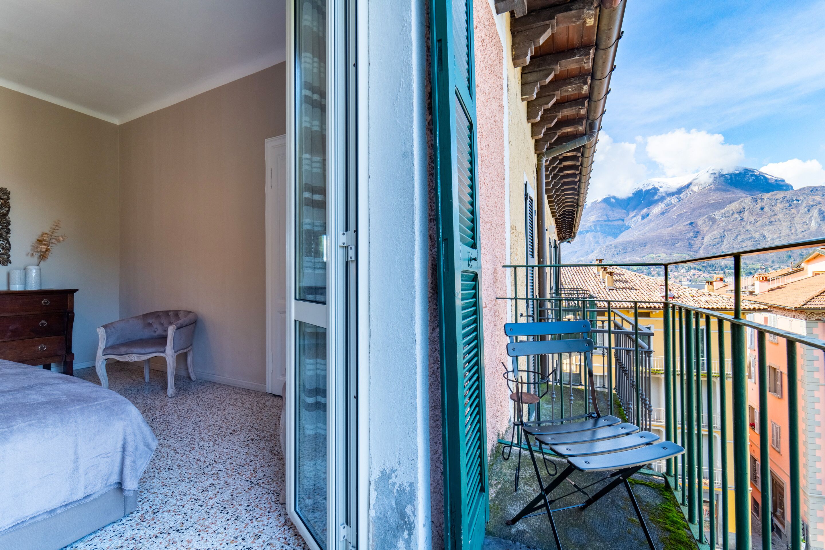 A balcony with a chair, a bed, and a view of mountains.