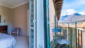 A balcony with a chair, a bed, and a view of mountains.