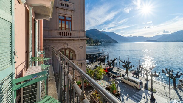 Un balcon donnant sur un lac et des montagnes, un fourgon garé et un immeuble doté d’un balcon.