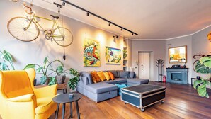 A living room with a sofa, a yellow armchair, a bicycle, and artwork on the walls. - Residenza Pasolini (Rome)