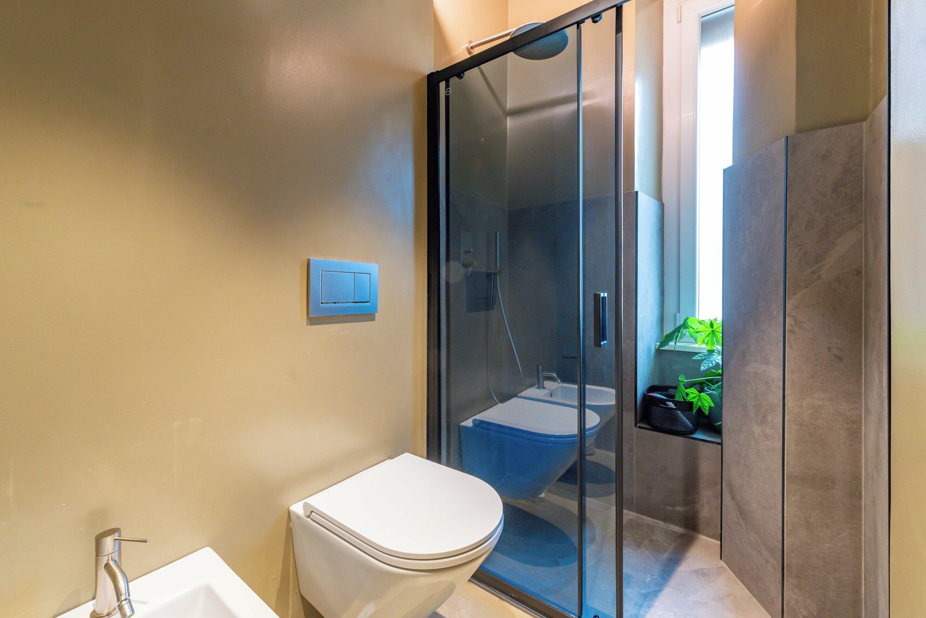 Une salle de bain moderne équipée de toilettes, d’un lavabo et d’une douche à parois en verre.