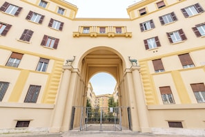 A building with a central archway, multiple windows with shutters, and a gated entrance. - Residenza Pasolini (Rome)