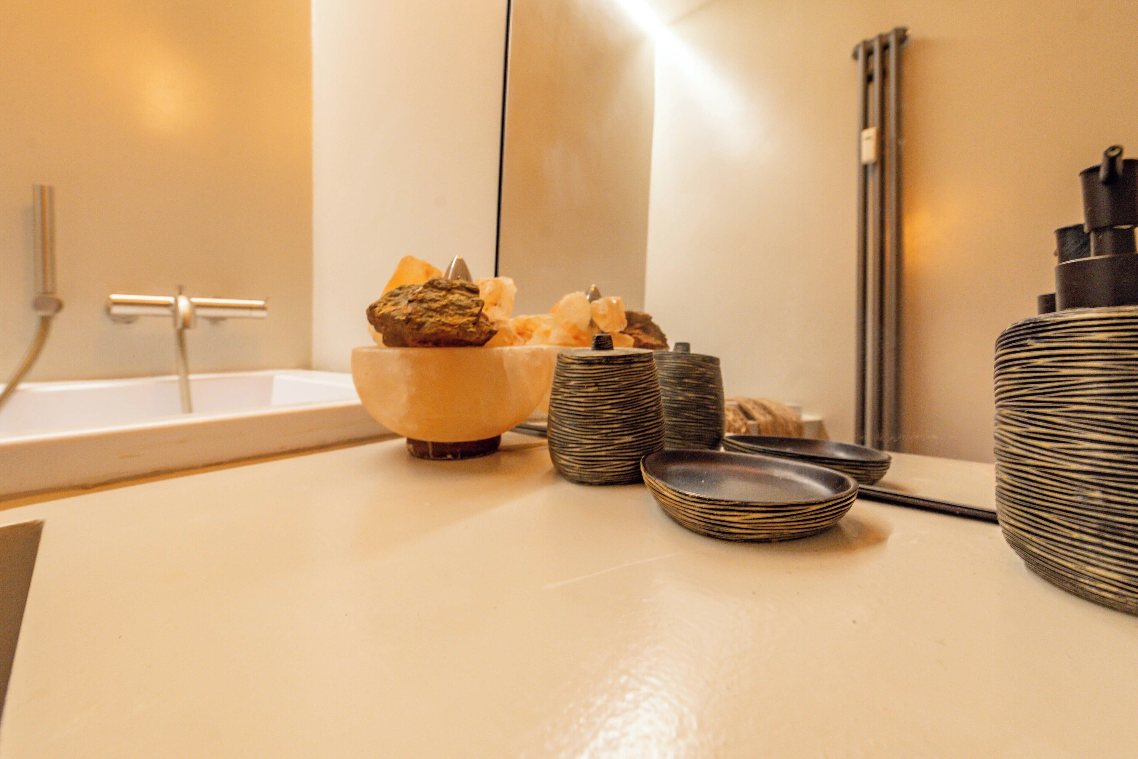 Een badkamer met een badkuip, een handdoekhouder en een wastafel met een verzameling toiletartikelen.