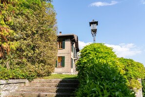 Ein Gebäude mit einer Steinaußenwand, grünen Fensterläden und einer Treppe, die zu ihm hinaufführt.