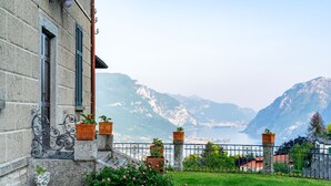 Ein Steinhaus mit einem Balkon mit Blick auf einen Bergsee.
