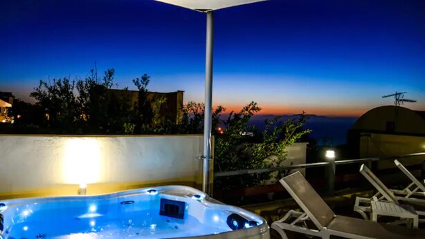 A hot tub with a sunset view, lounge chairs, and a pergola structure. - Sunset Horizon Oia (Santorini)