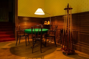 Ein Zimmer mit einem grünen Tisch, Holzstühlen, einer Lampe und einem hohen Dekorationsgegenstand.