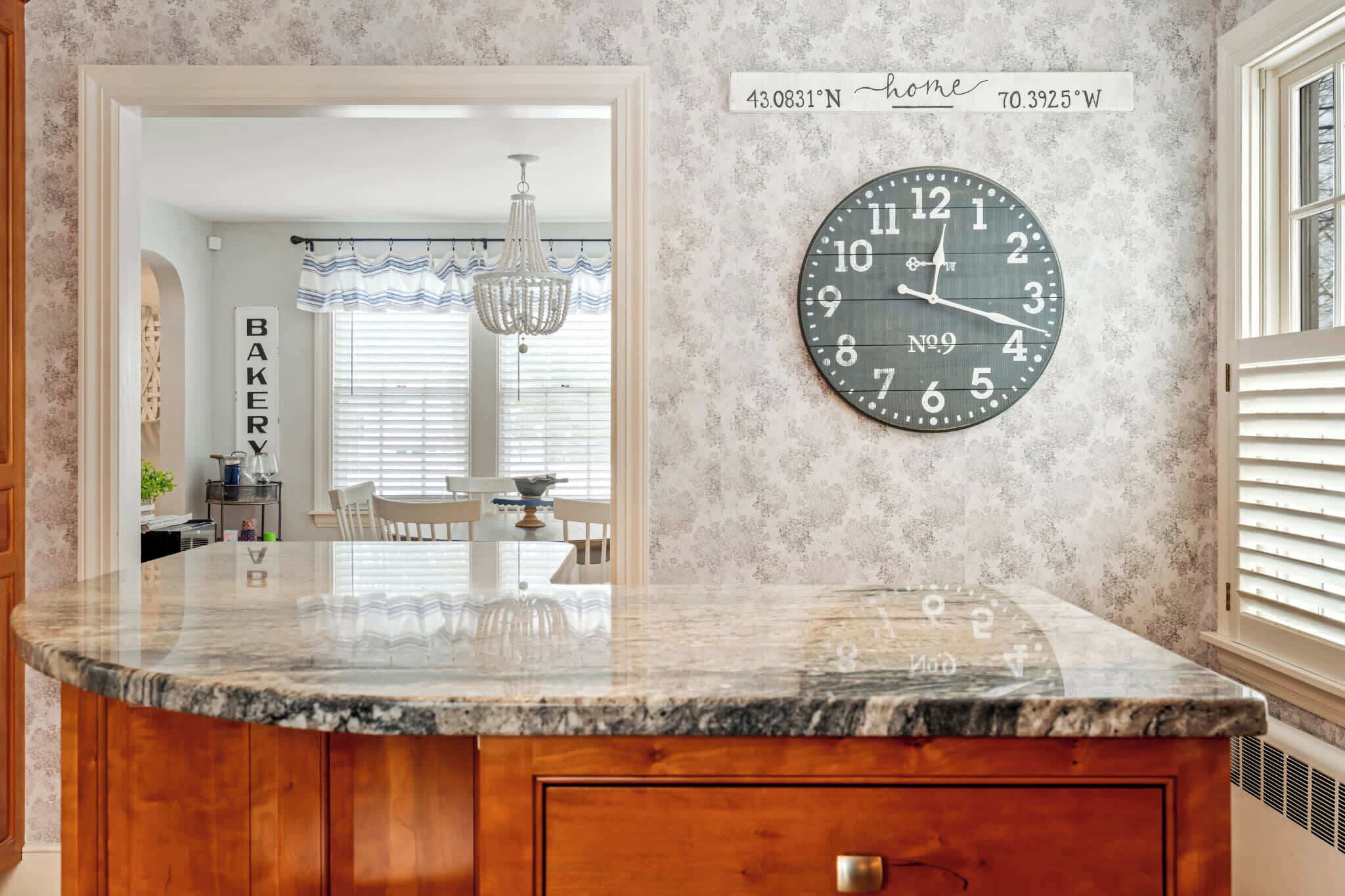 A kitchen with a marble countertop, a wall clock, and a 'BAKERY' sign.