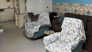 En stue med blå væg, et hvidt skab, et ur og en sofa med mønster.