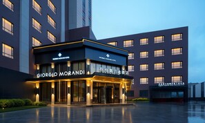 A modern hotel entrance with illuminated signage, a glass facade, and a well-lit driveway. - Giorgio Morandi Hotel - Bazhou (Langfang)
