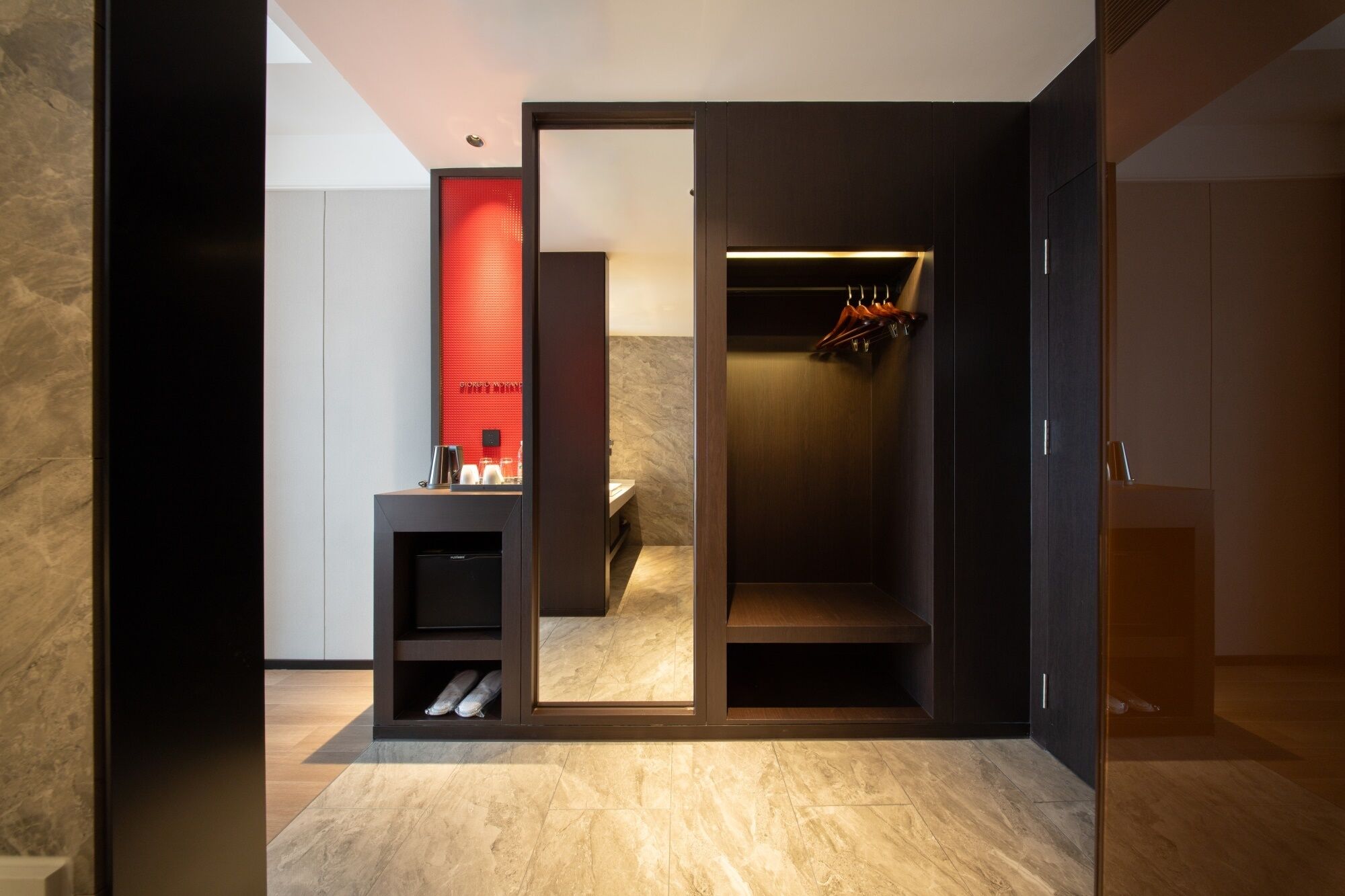 A modern bathroom with a shower, a vanity with a mirror, and a red accent wall.