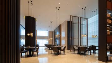 A modern interior with tables and chairs, pendant lighting, and a large window.