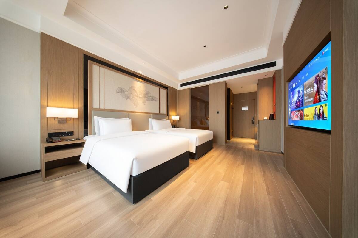Habitación de hotel con una cama grande, mesitas de noche, un televisor de pantalla plana y piso de madera.