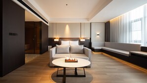 A modern hotel room with a sofa, a round coffee table, and a bed with a headboard. - Giorgio Morandi Hotel - Bazhou (Langfang)