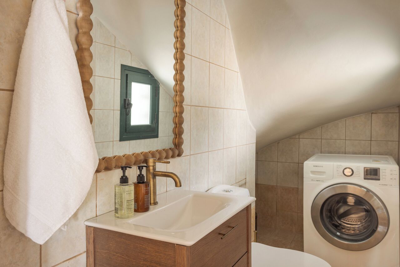 A bathroom with a sink, mirror, towel, and washing machine.