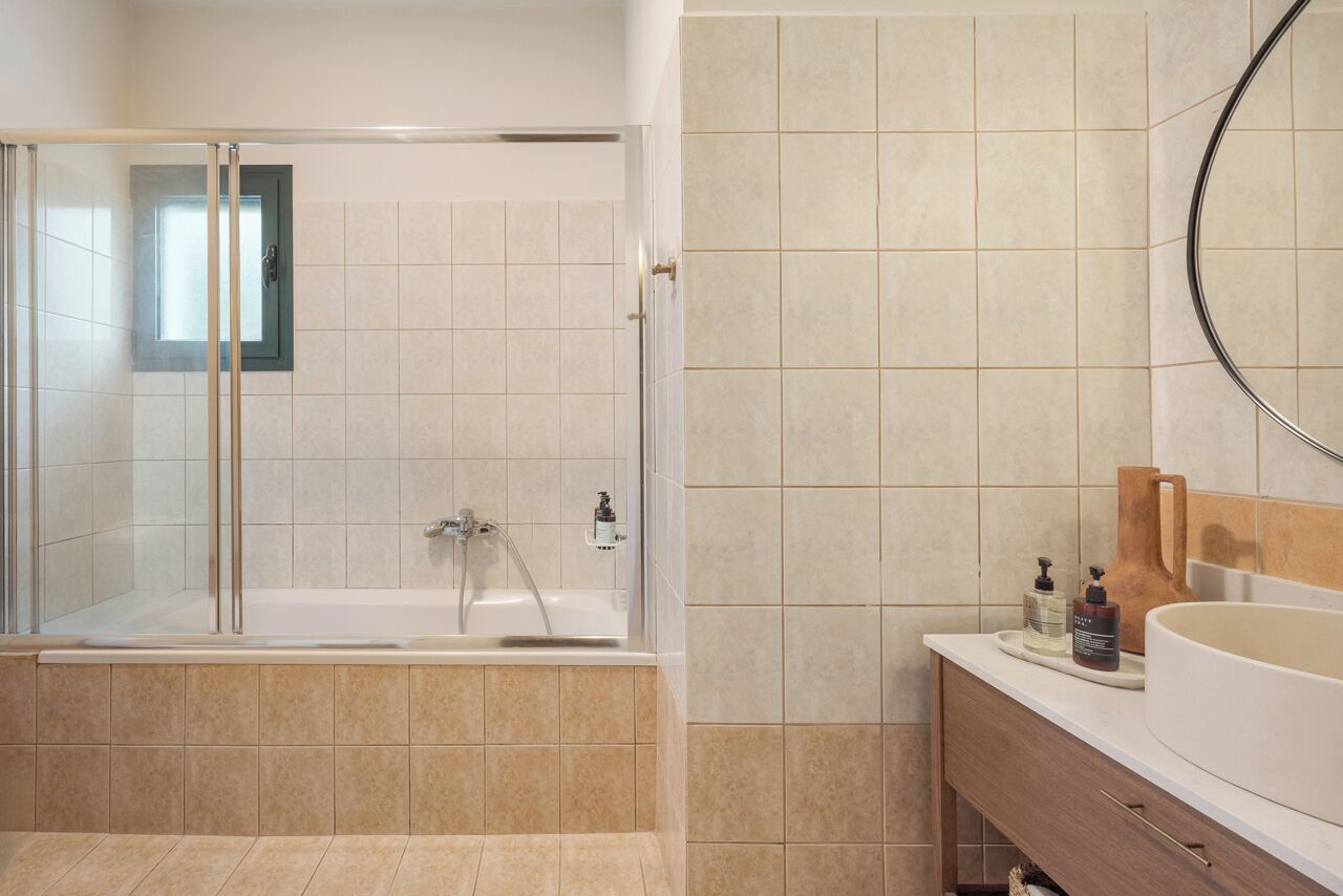 Une salle de bain moderne avec une douche à parois de verre, une baignoire et un meuble-lavabo doté d’un évier et d’un miroir.