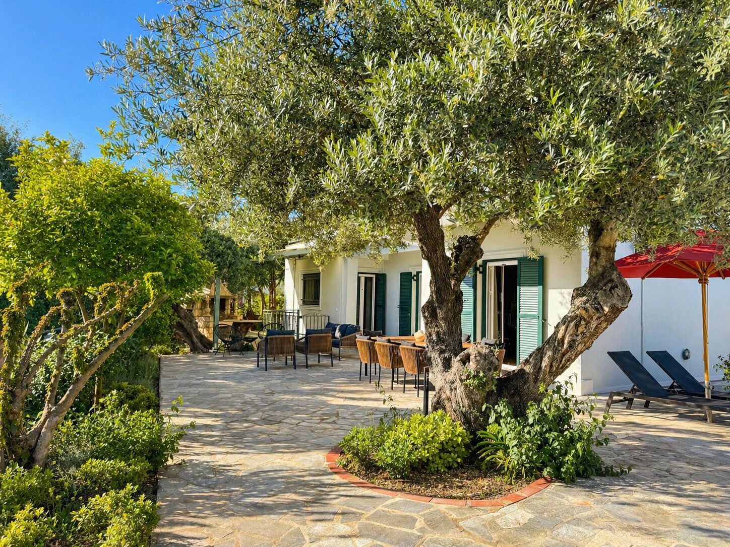 A courtyard with stone flooring, outdoor seating, and a tree.