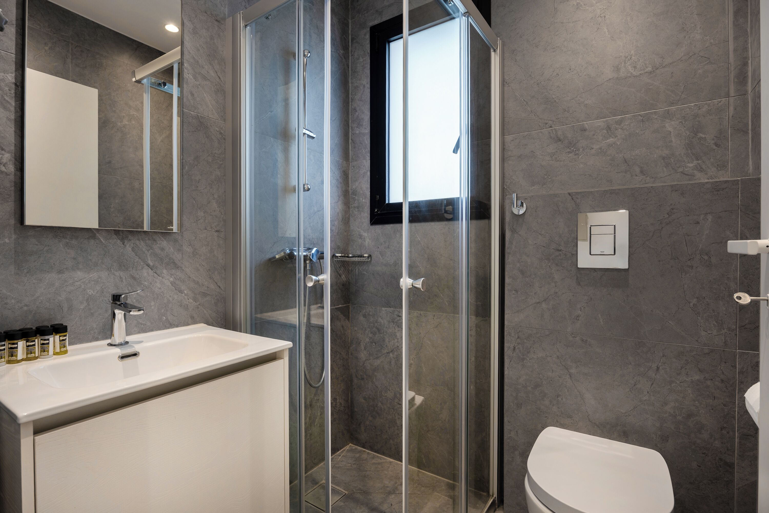 Une salle de bain moderne avec une douche à parois de verre, un lavabo blanc et des toilettes.