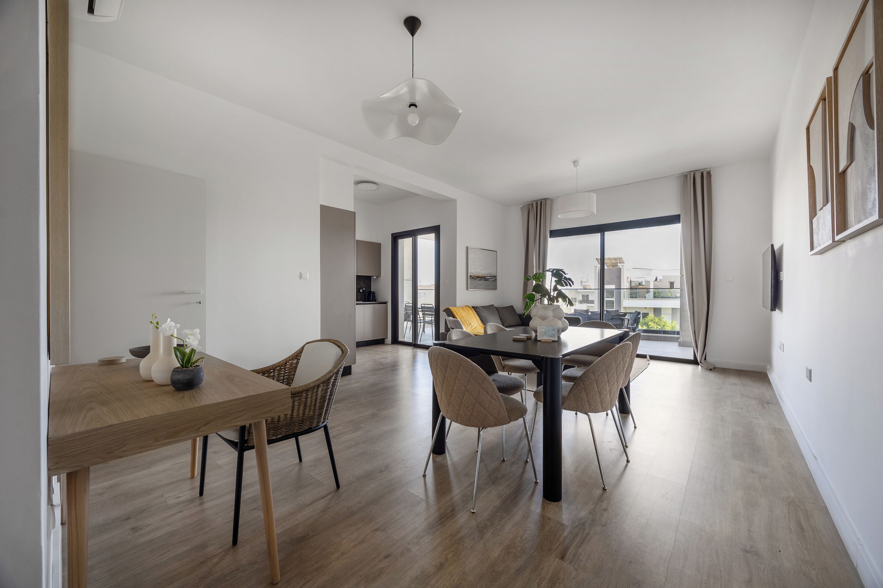 Una sala de estar moderna con comedor, que presenta un comedor de madera, sillas de mimbre y una lámpara colgante contemporánea.