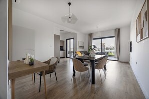 Ein modernes Wohnzimmer mit Essbereich, mit einem Holztisch, Korbstühlen und einer zeitgemäßen Pendelleuchte.