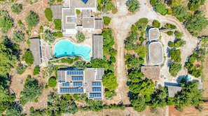 An aerial view of a residential area with a swimming pool, solar panels, and a large building with a unique roof design. - 'Il Trullo - Tia Maria Country Inn' with Hot Tub (Racale)