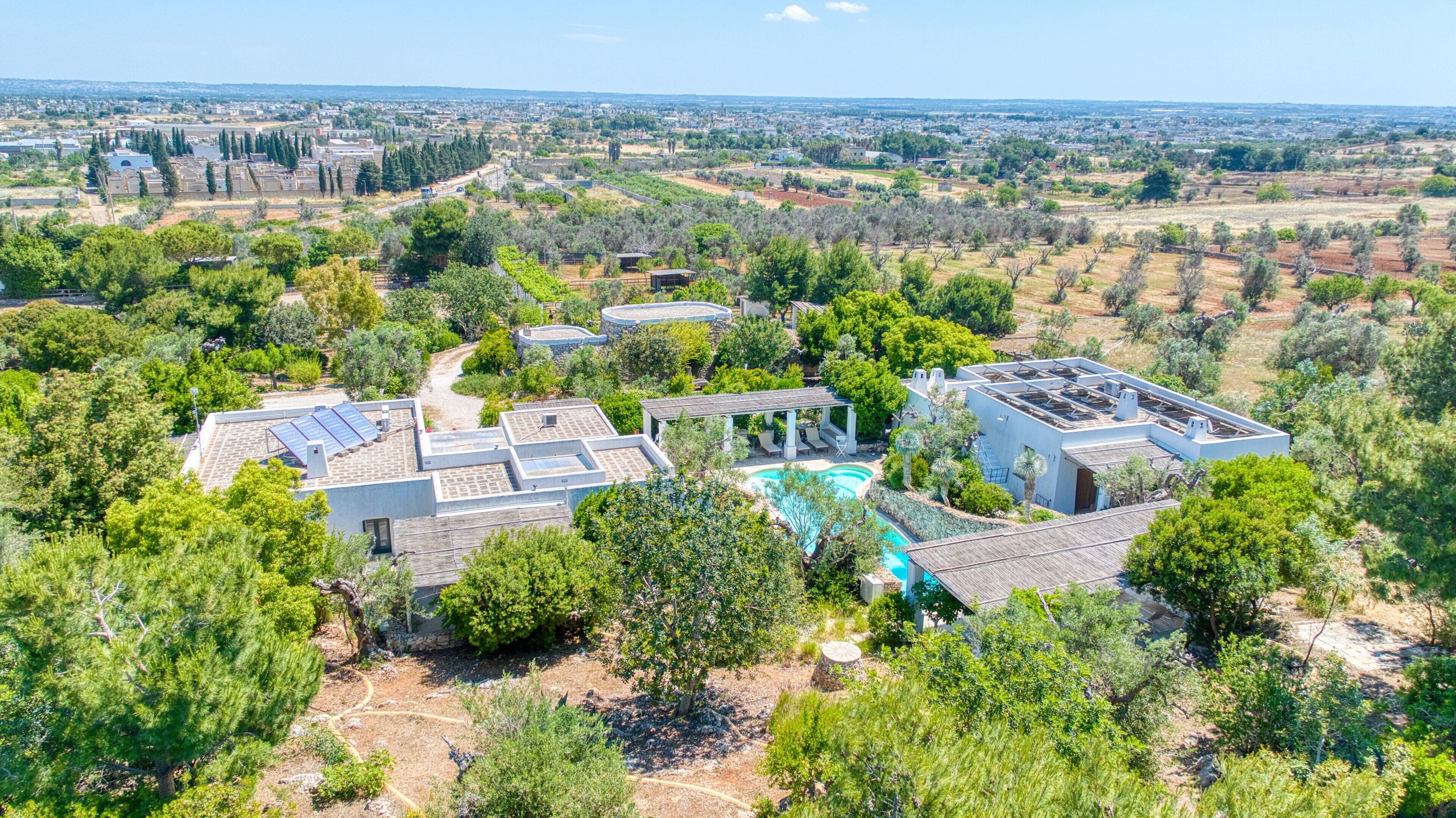 A residential area with multiple houses, a swimming pool, and surrounding greenery.