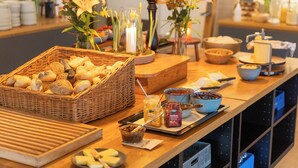 A buffet setup with bread, condiments, and a candle centerpiece. - Den Gamle Smedje (Fjerritslev)