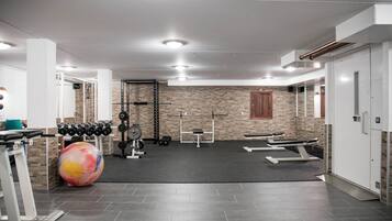 A gym with exercise equipment, a large exercise ball, and a brick wall.