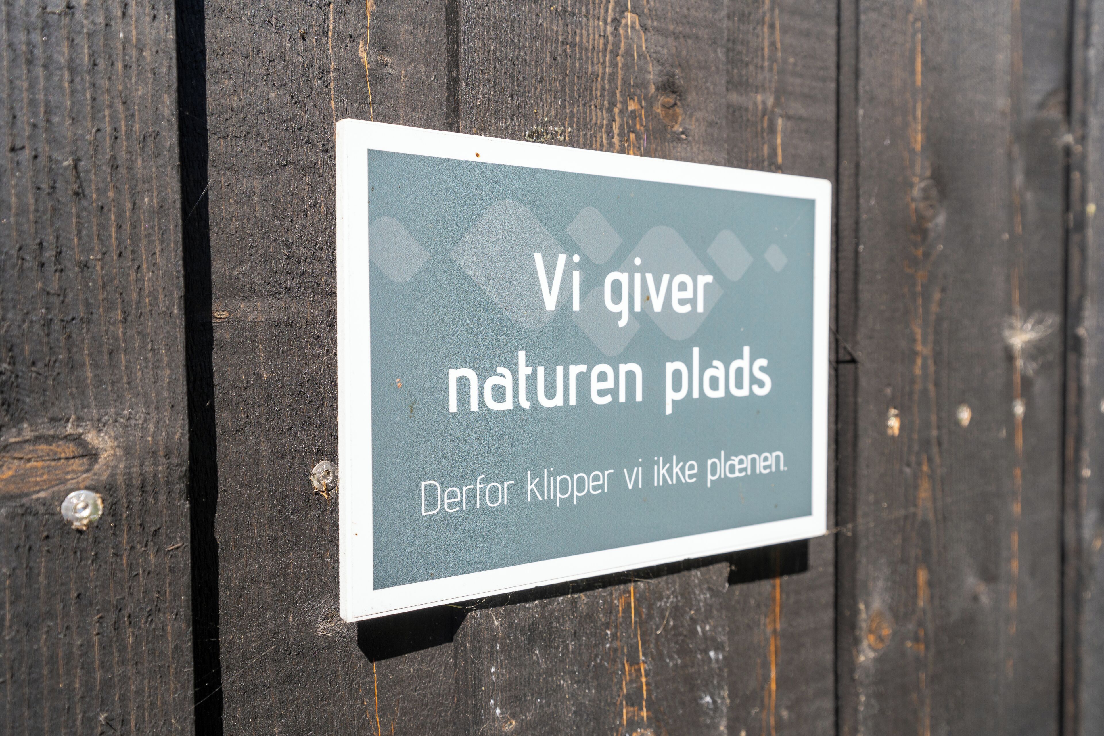 A sign with text in a foreign language, mounted on a wooden surface.