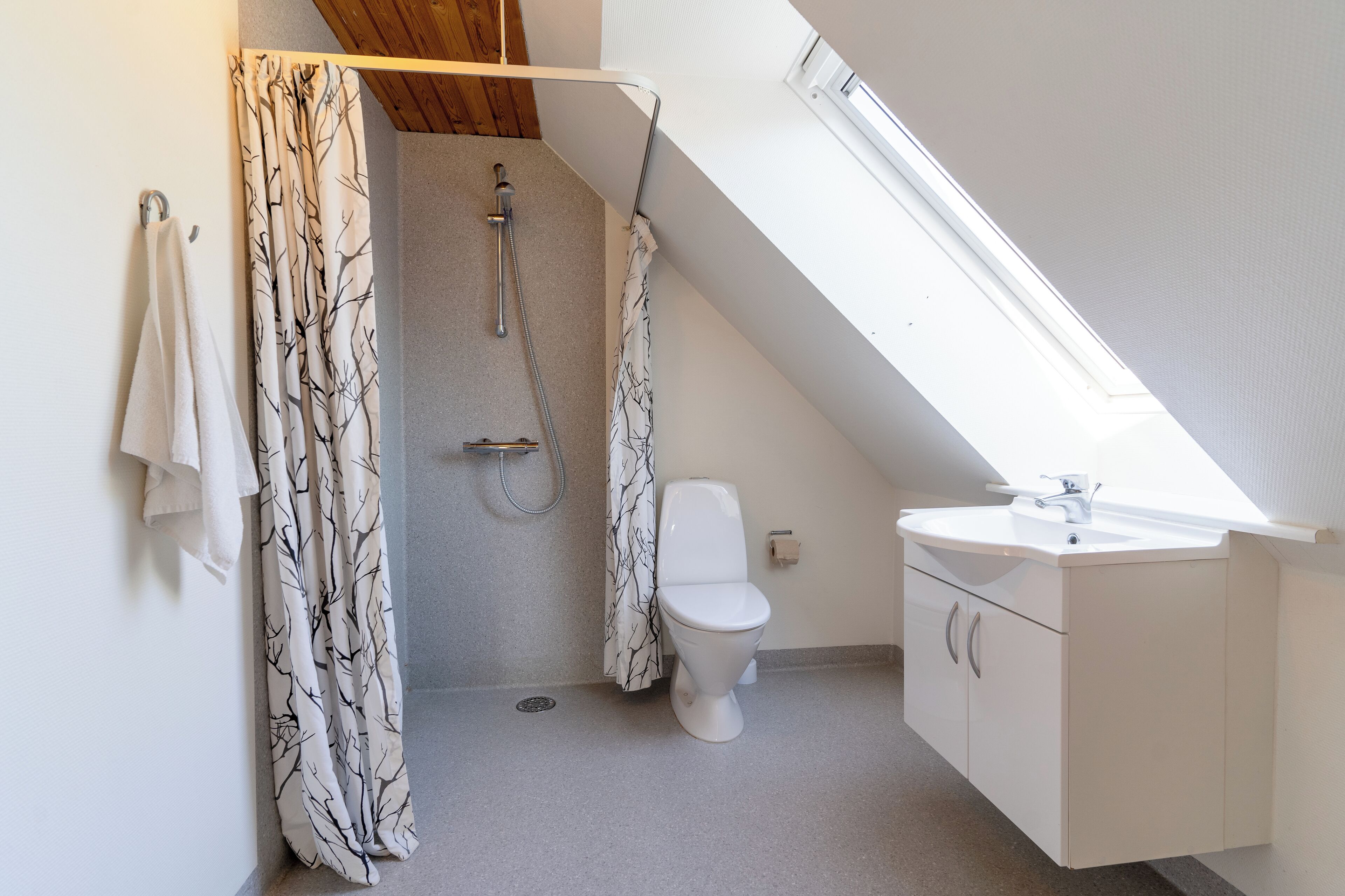 Un baño pequeño y moderno con ducha, inodoro y lavamanos.