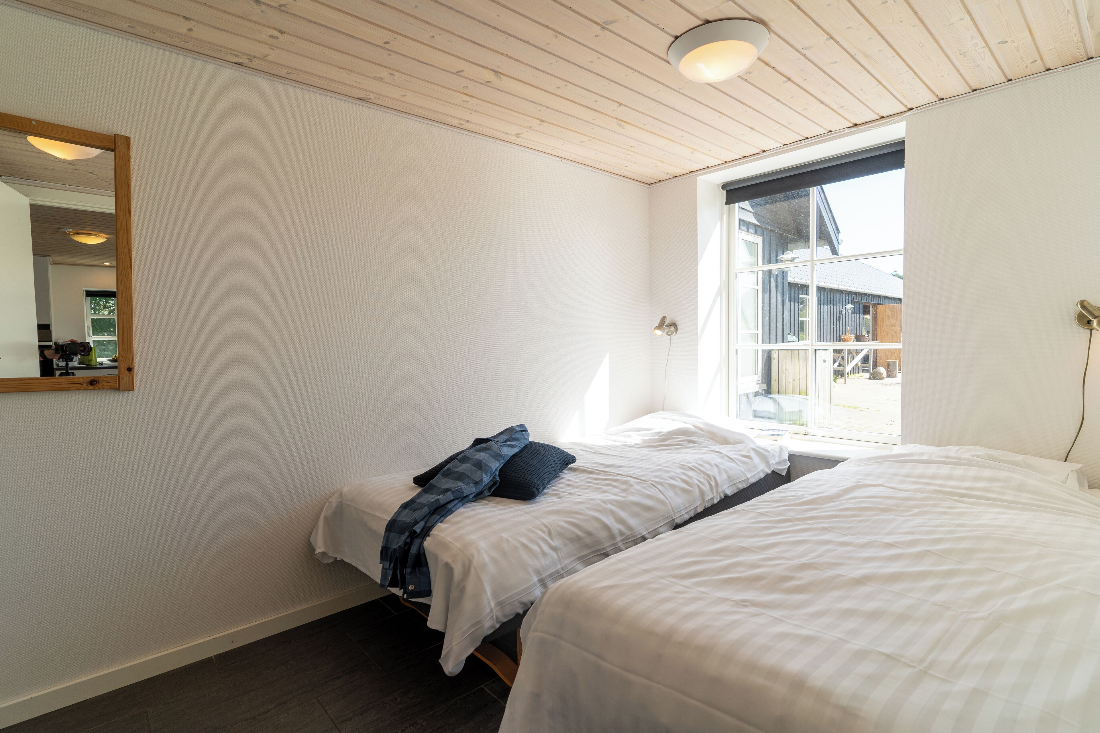 Un dormitorio con dos camas, un ventanal grande y techo de madera.