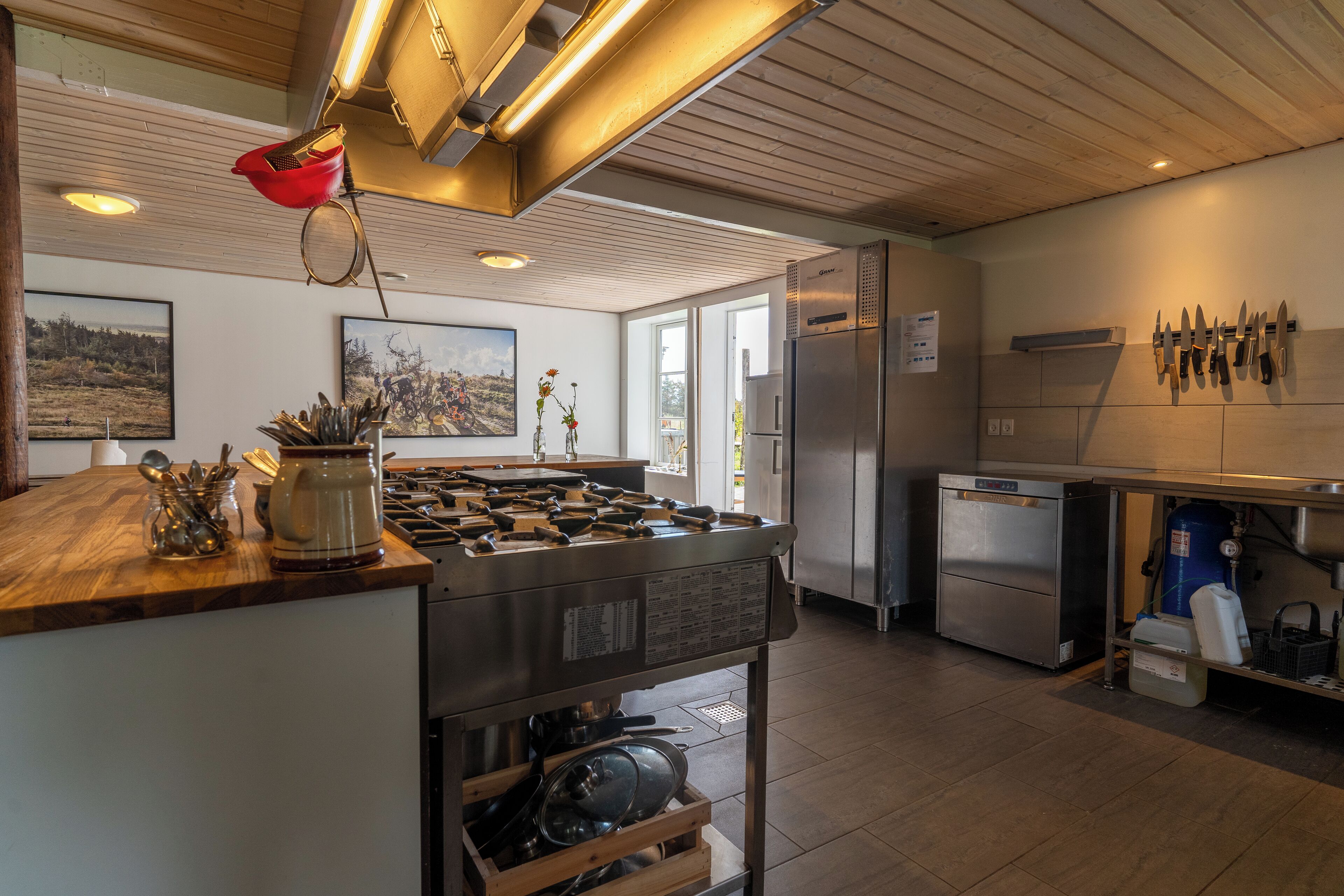 A modern kitchen with a central island, stainless steel appliances, and a variety of utensils and cookware.