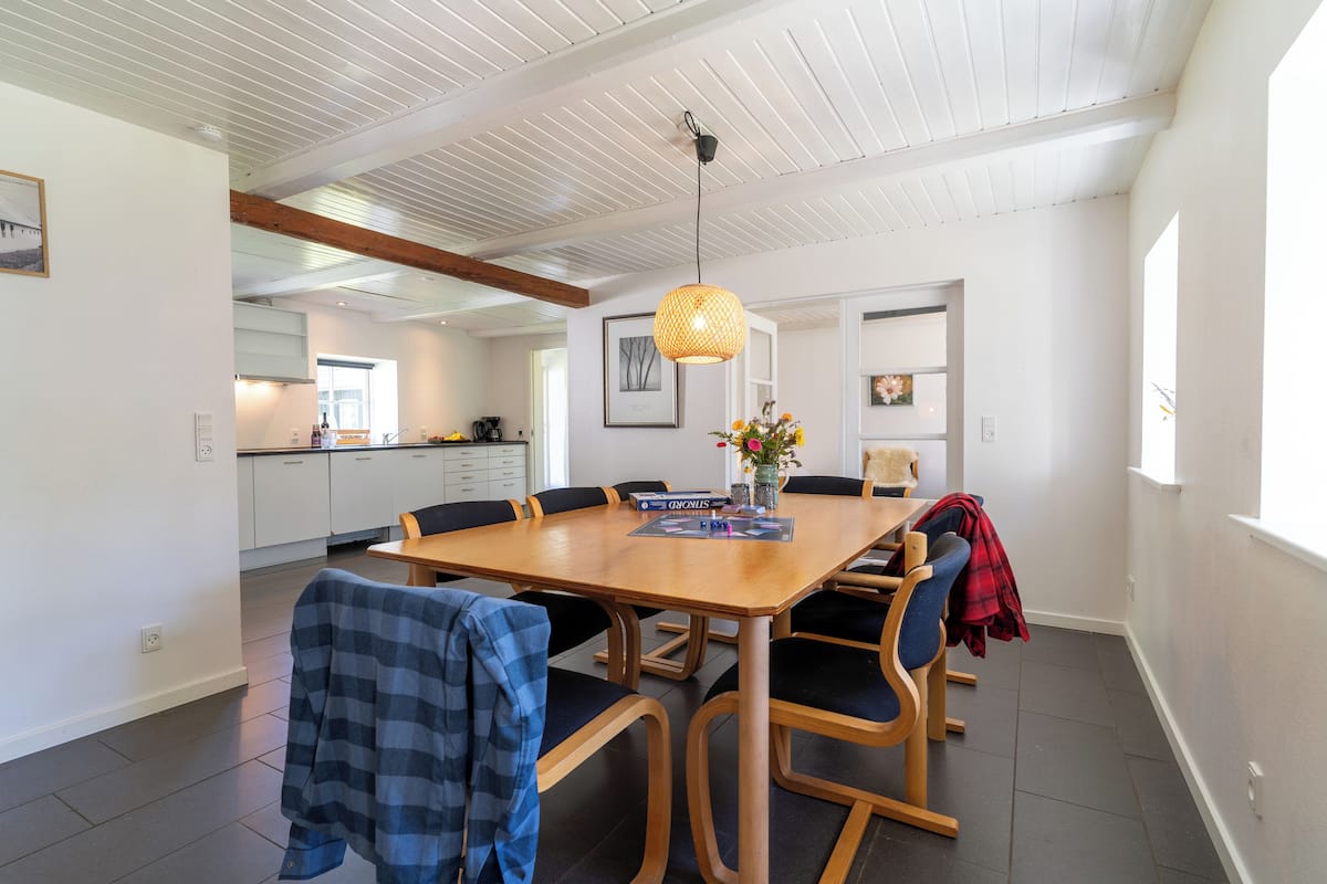 A dining area with a wooden table, black upholstered chairs, and a hanging light fixture.