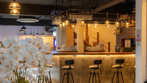 A bar area with a marble counter, bar stools, hanging pendant lights, and a potted plant. - Host'S EL Fisherman (Koh Samui)