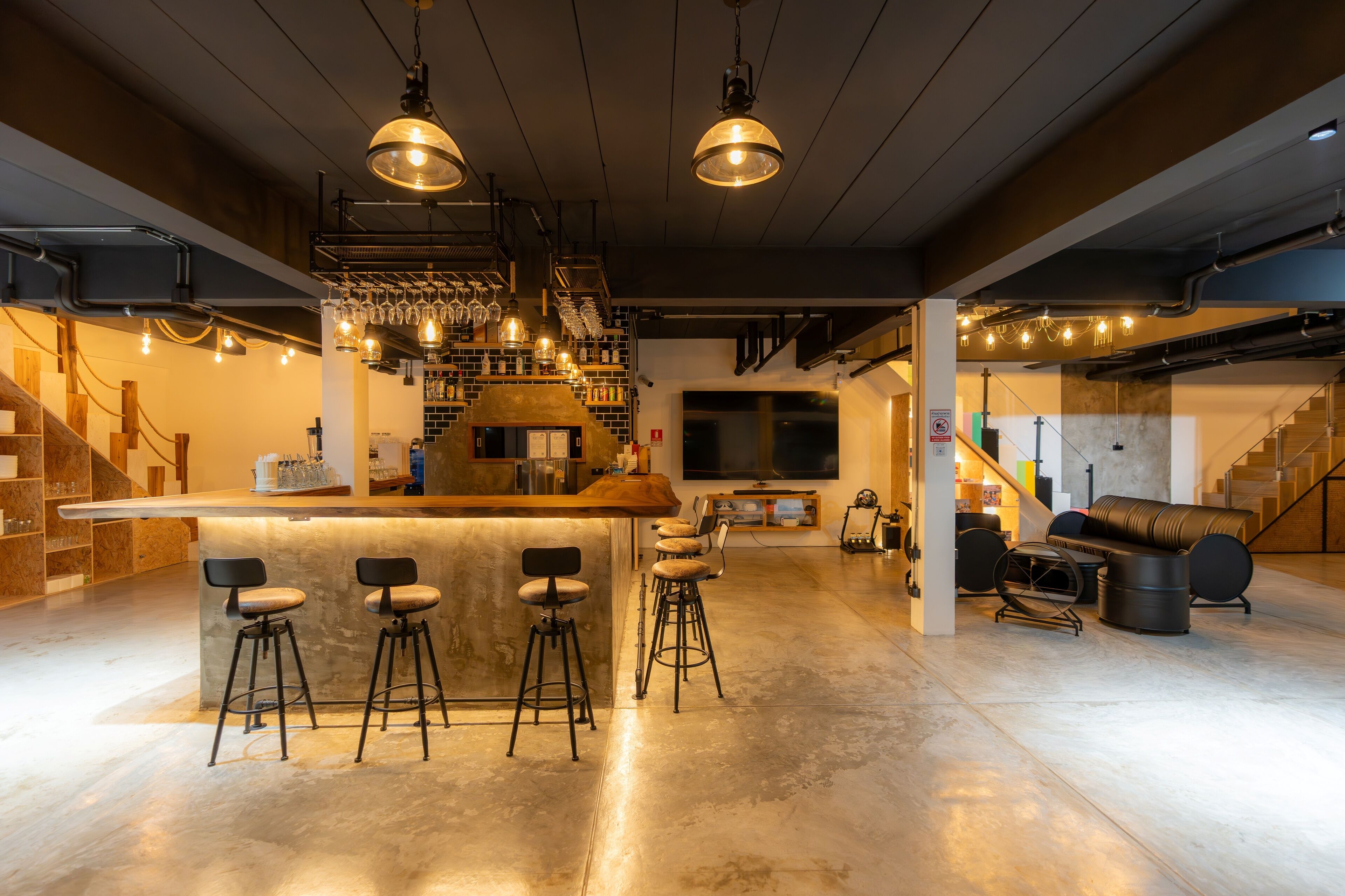 Uma área de bar moderna com banquetas, balcão e luminárias pendentes.