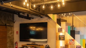 A modern lounge area with a large flat-screen TV, comfortable seating, and a staircase with colorful steps. - Host'S EL Fisherman (Koh Samui)