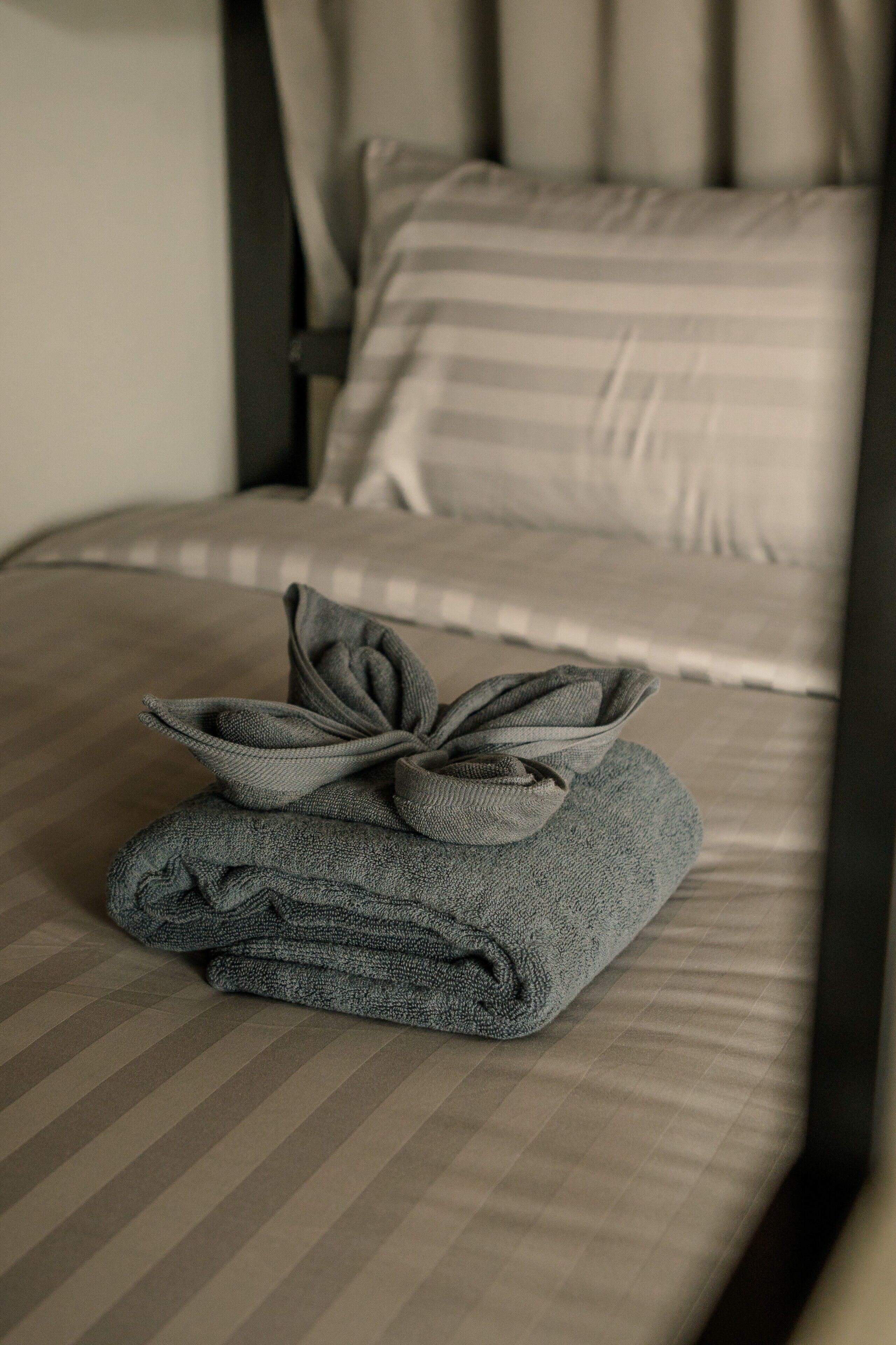 Una cama bien hecha con ropa de cama a rayas y una toalla doblada con un lazo.