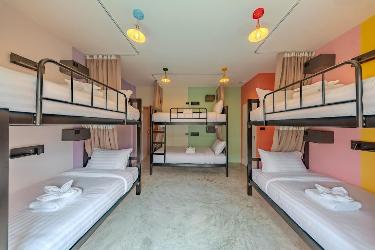 Un dormitorio con literas, un escritorio pequeño y una ventana con cortinas.