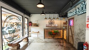 A reception area with a wooden bench, a neon sign reading "Host's EL", and a fire extinguisher on the wall. - Host'S EL Fisherman (Koh Samui)