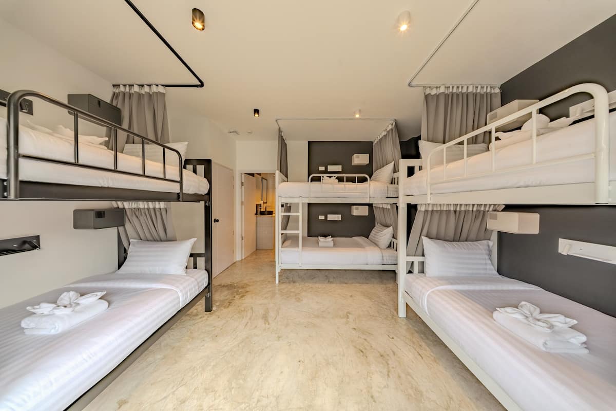 Habitación de hotel con literas, un kitchenette pequeño y un baño visible a través de una puerta abierta.