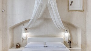 Un dormitorio con cama, lámparas de noche, mesitas de noche y dosel.