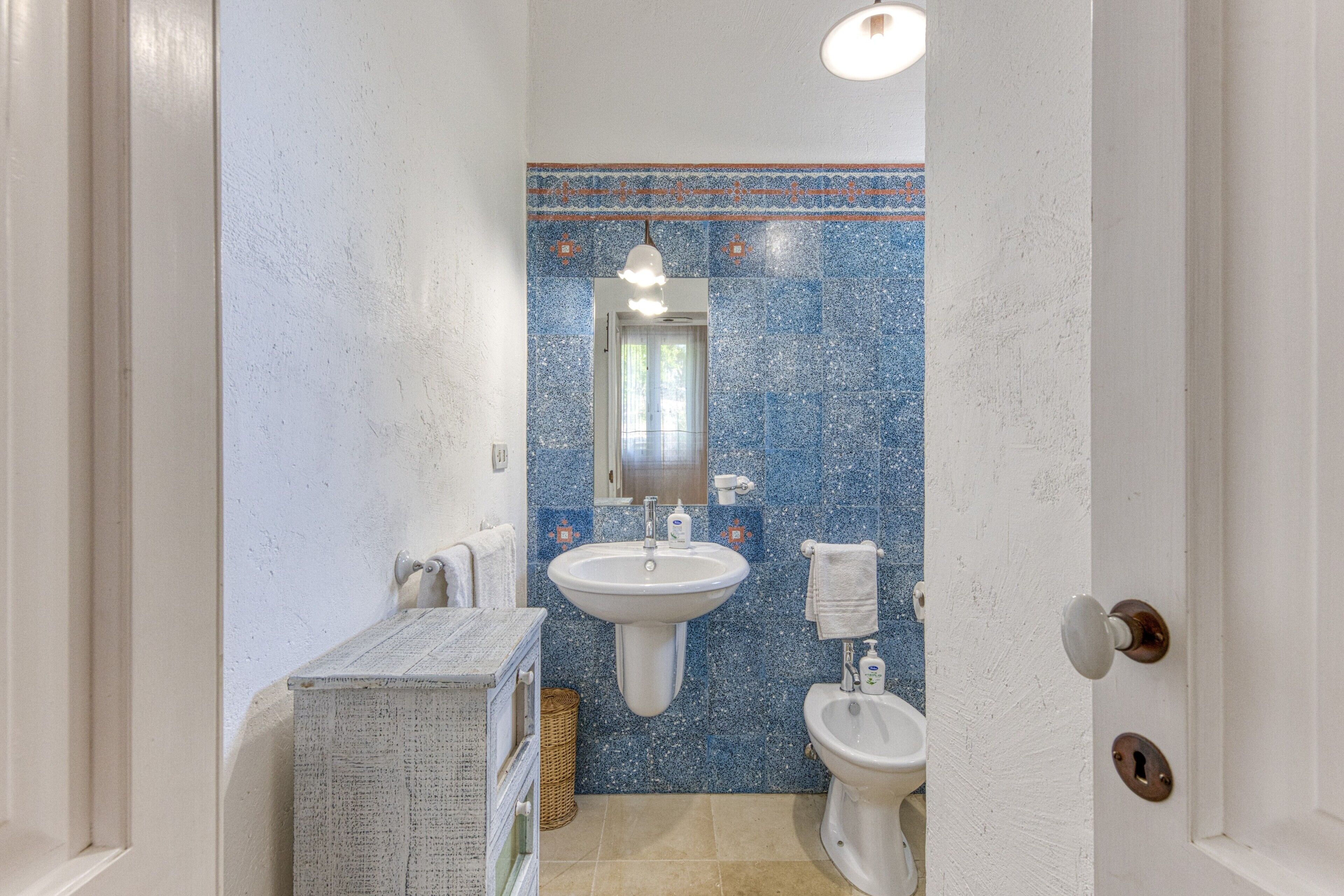 Et badeværelse med vask, toilet og spejl.