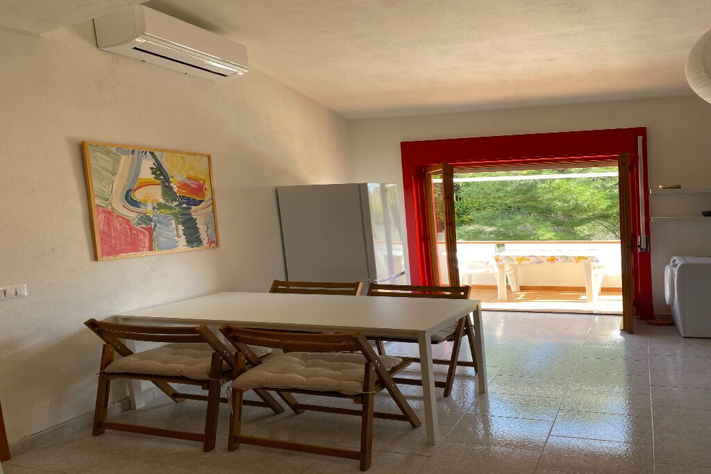 Un comedor con una mesa y sillas, un refrigerador y un cuadro en la pared.