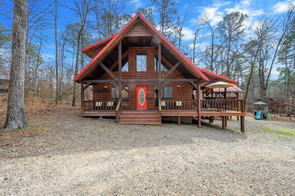 A log cabin with a red roof, a front porch, and a small deck. - Kodiak Bear-hot Tub-playground-location! (Broken Bow)
