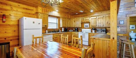 A wooden cabin-style kitchen with a central island, wooden cabinets, and a dining table with chairs.