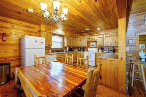 A wooden cabin-style kitchen with a central island, wooden cabinets, and a dining table with chairs.