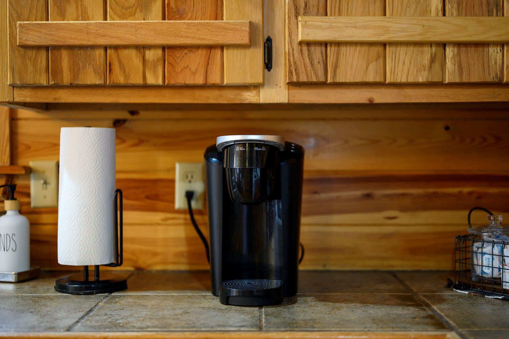 A coffee maker on a kitchen counter with wooden cabinets in the background.