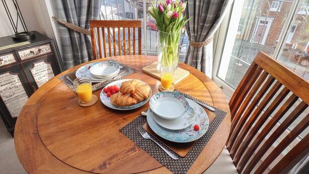 Un tavolo da pranzo con piatti, croissant e un vaso di fiori.