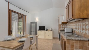 Una cocina compacta con comedor, televisión integrada y microondas.
