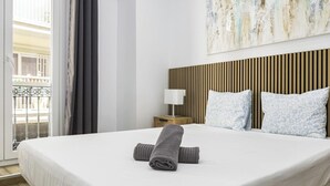 A hotel room with a large bed, a nightstand with a lamp, and a view of a balcony. - Perfect destination in the historic center (Málaga)